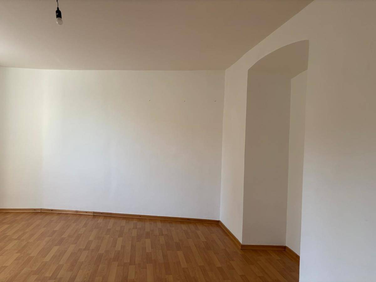 Heller Raum mit Laminatboden und einer architektonischen Nische, bereit zur individuellen Gestaltung.