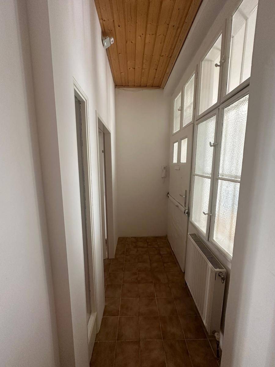 Heller Eingangsbereich mit Holzdecke und Fliesenboden, führt zu weiteren Räumen.