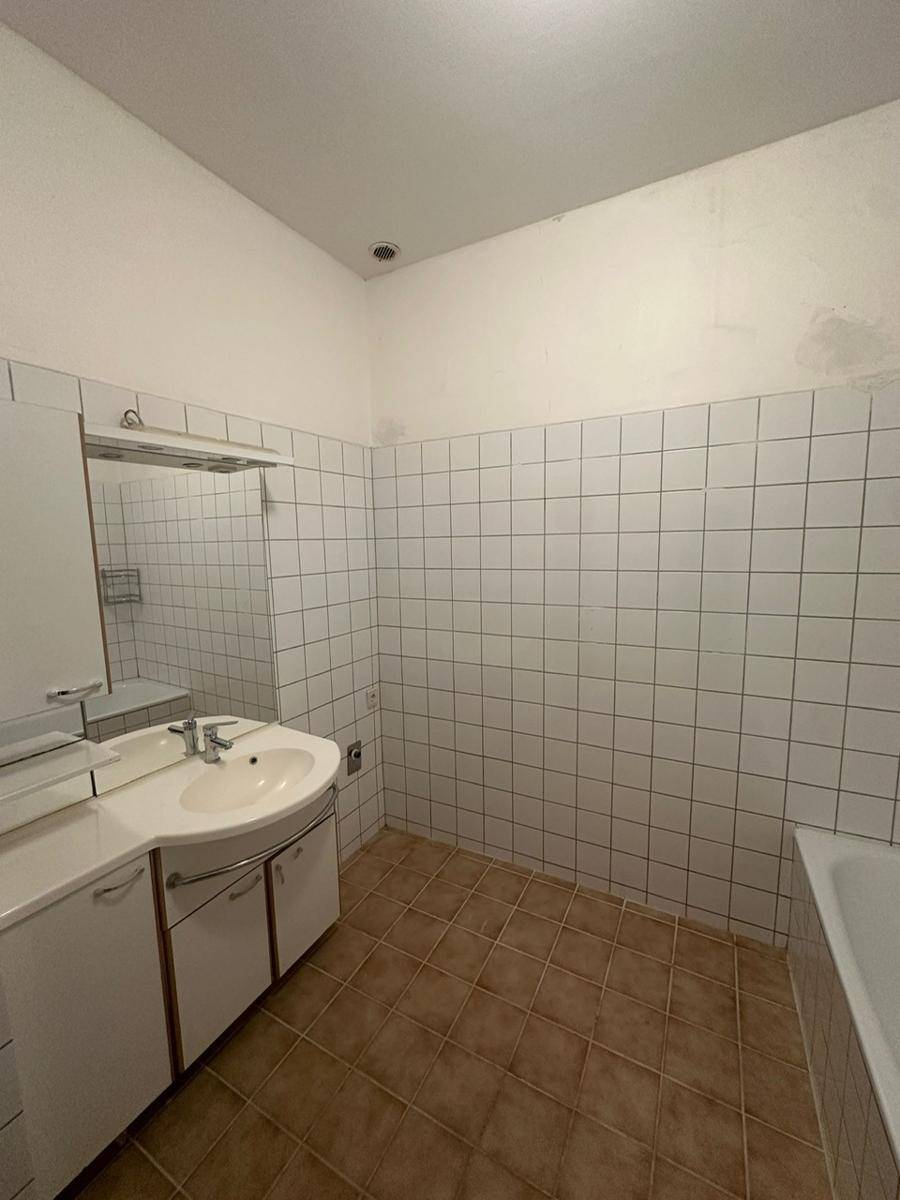 Badezimmer mit Waschbecken, Spiegelschrank und weißen Wandfliesen.