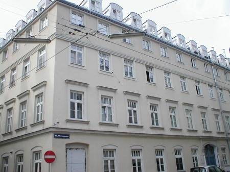 Historisches Eckgebäude mit vielen Fenstern und klassischer Architektur.