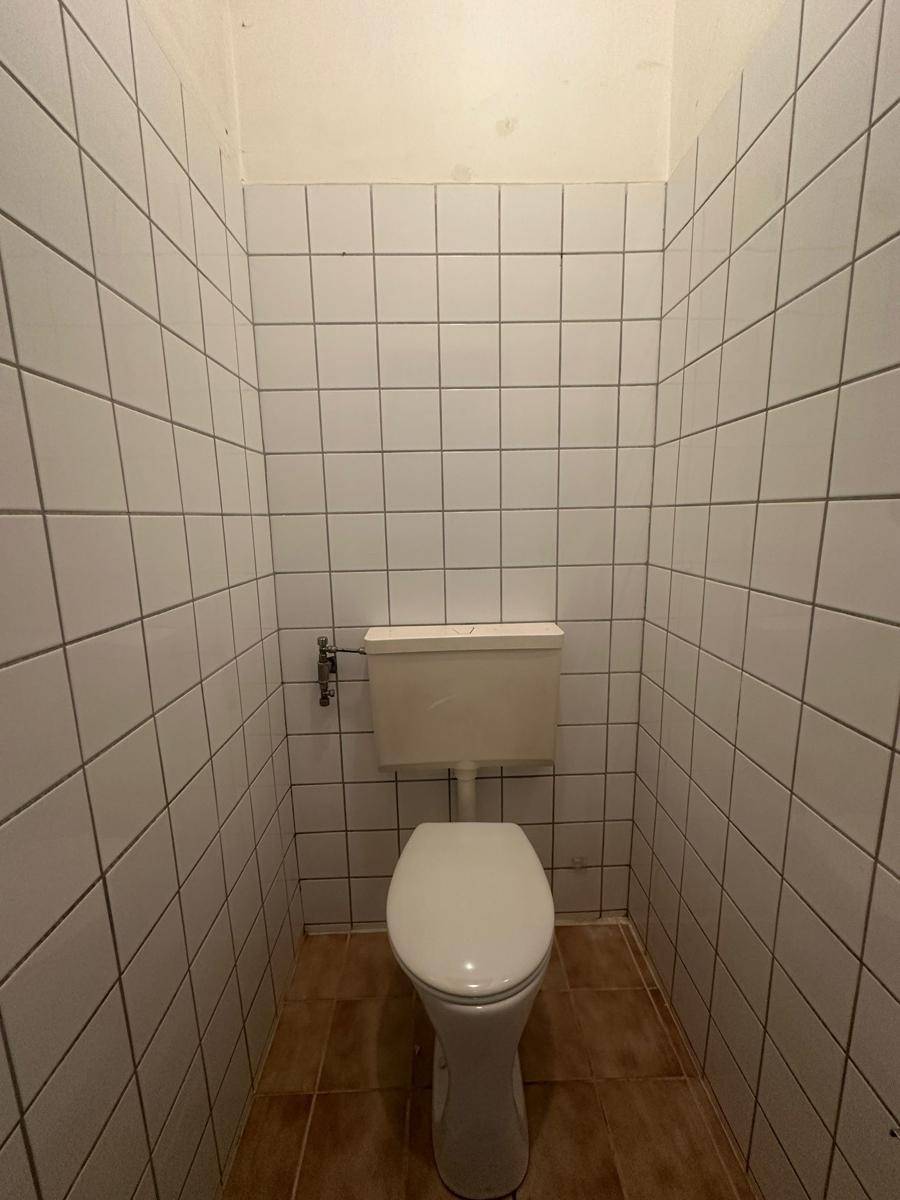Separates WC mit weißen Fliesen an Wänden und Boden.
