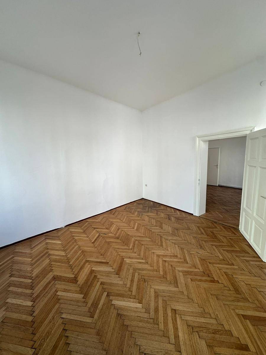 Leeres Zimmer mit klassischem Fischgrätparkett und frisch gestrichenen Wänden.
