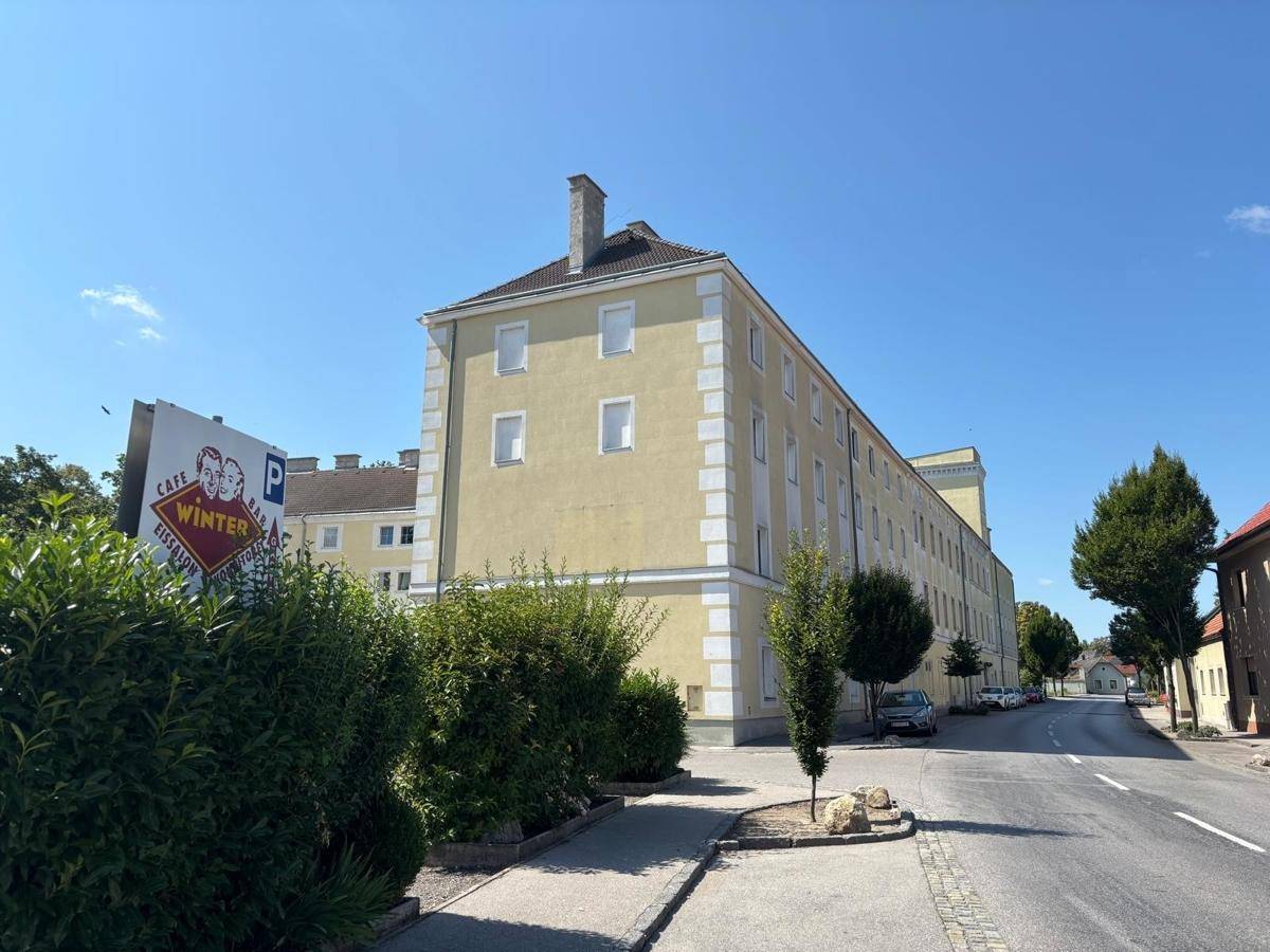Seitenansicht eines gelben Gebäudes mit Satteldach und umliegender Straße.