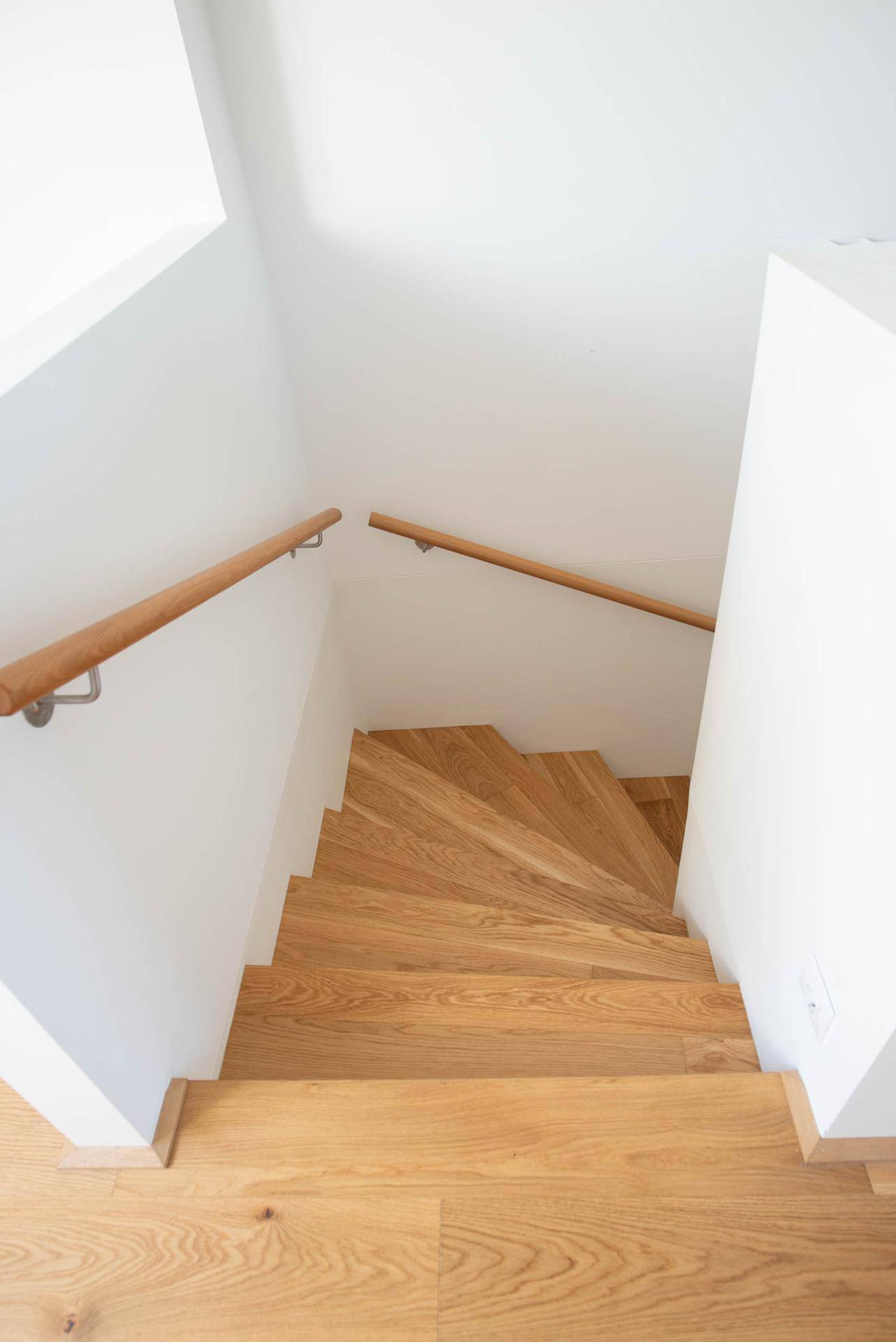 Moderne Holztreppe mit elegantem Holzgeländer, die die verschiedenen Ebenen verbindet.