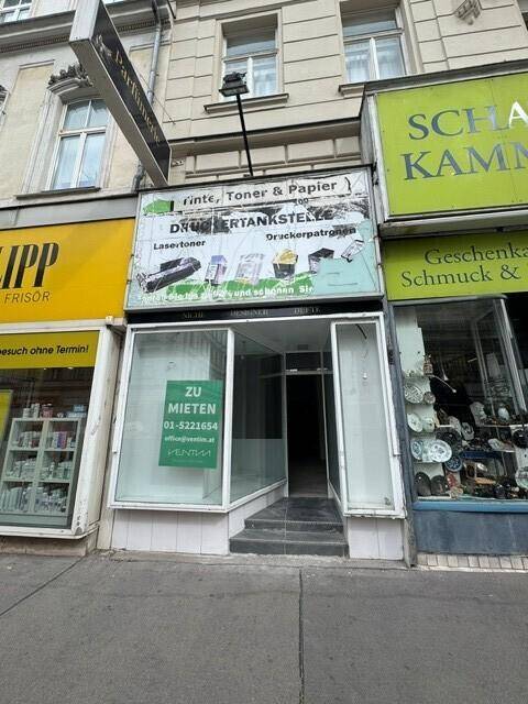 Nahaufnahme eines Ladenlokals im Erdgeschoss mit großen Schaufenstern und einem 'Zu vermieten'-Schild.