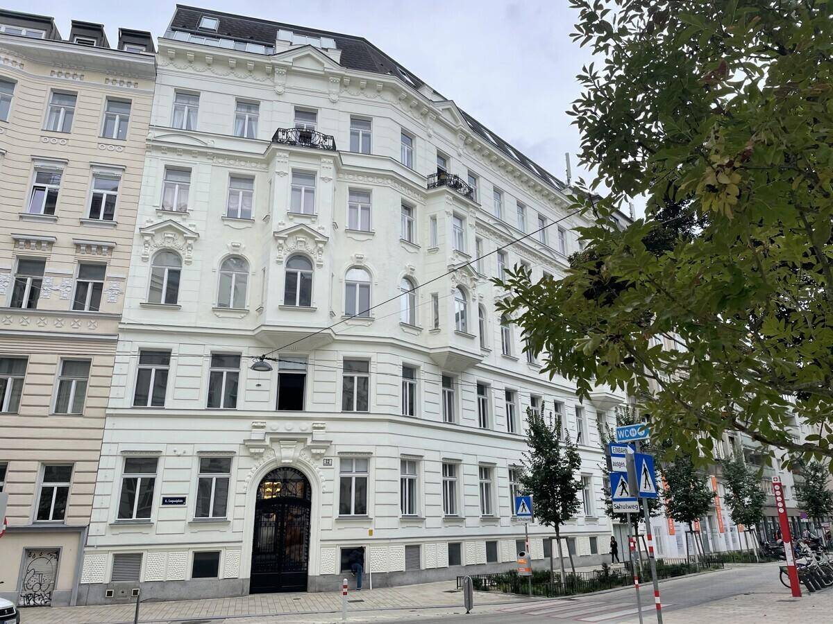 Historisches Gebäude mit klassischer Architektur, weißer Fassade und dekorativen Balkonen an einer Stadtstraße.