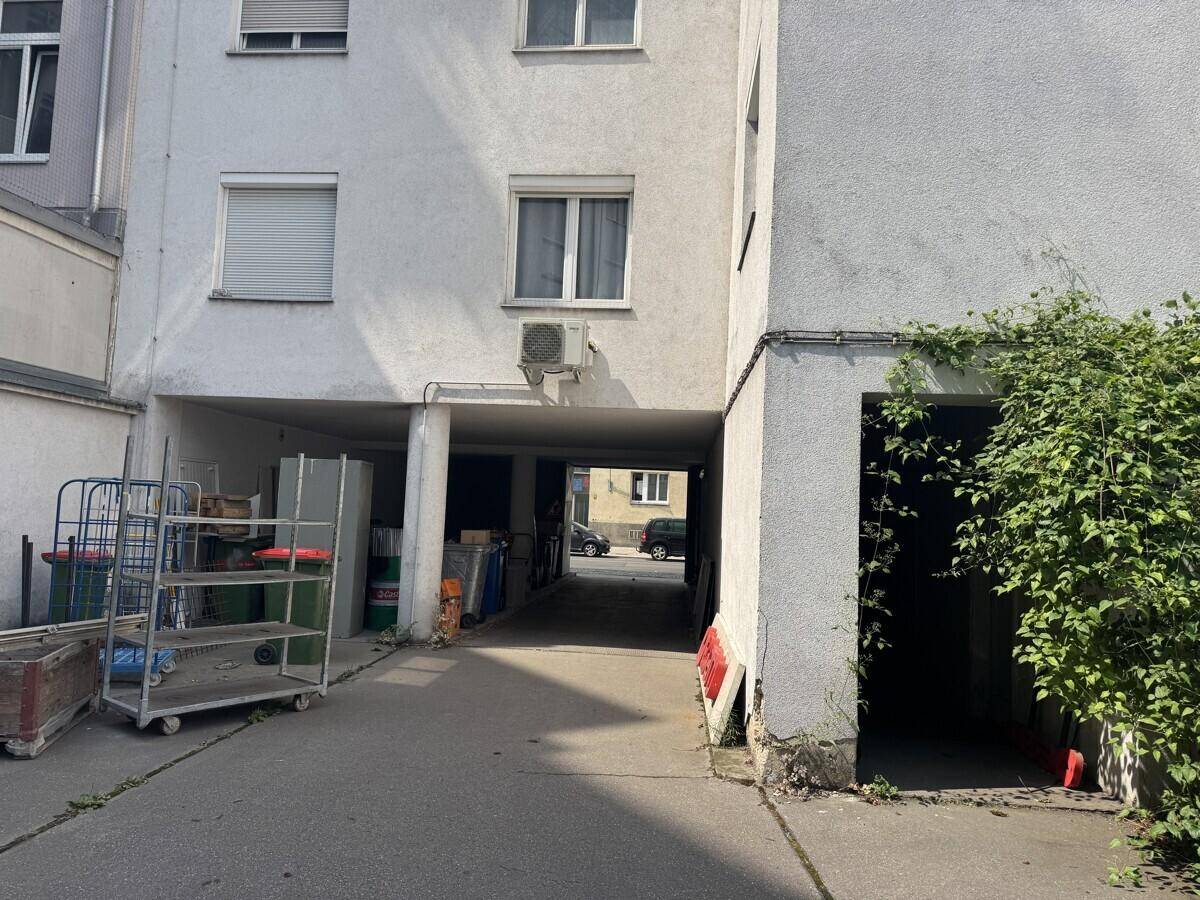 Überdachte Zufahrt oder Durchgangsbereich eines Gebäudes mit Blick auf die Straße im Hintergrund.