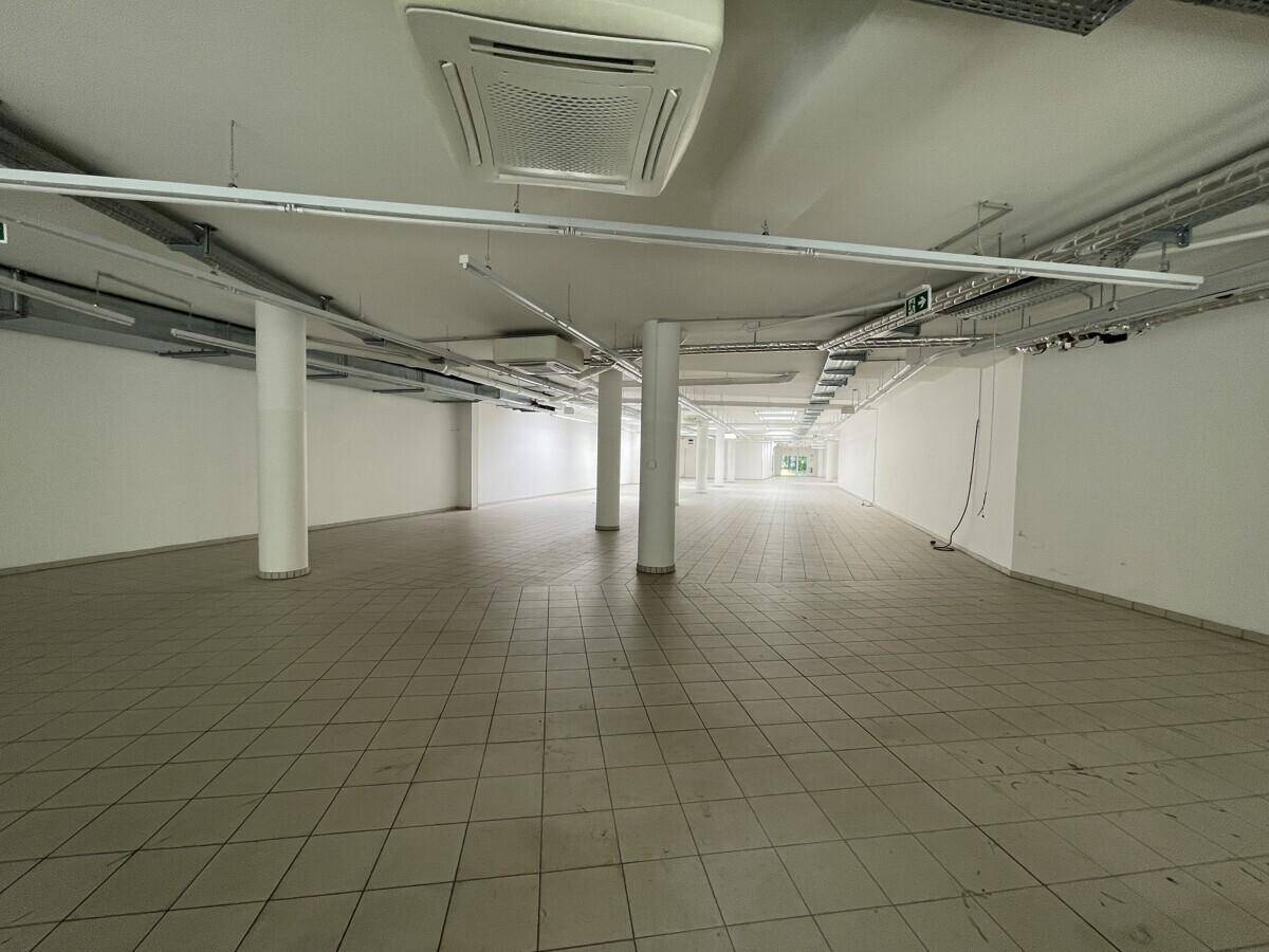 Weitläufiger Gewerberaum mit vielen Säulen, Fliesenboden und Deckenfenstern für Tageslicht.