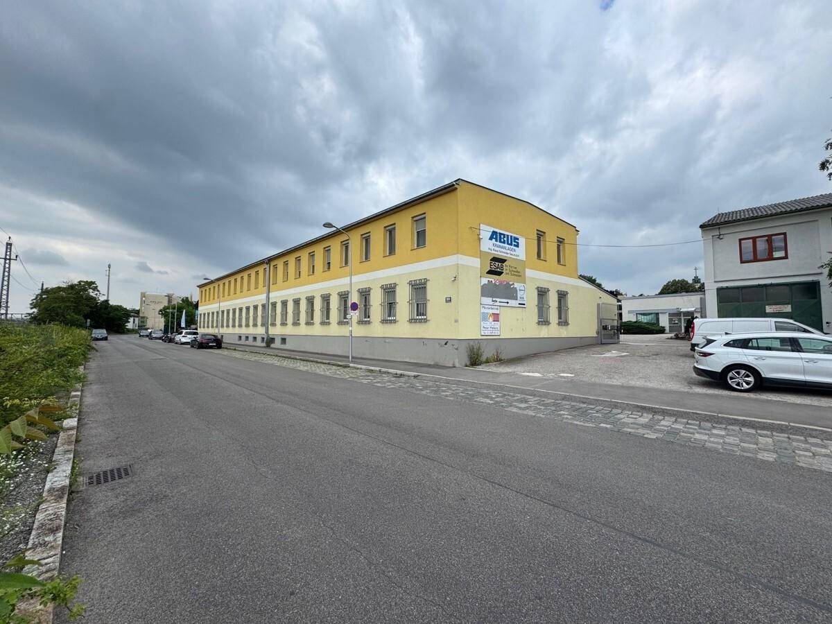 Langes, gelbes Geschäftsgebäude entlang einer Straße mit Parkplätzen und einem ABUS-Schild.