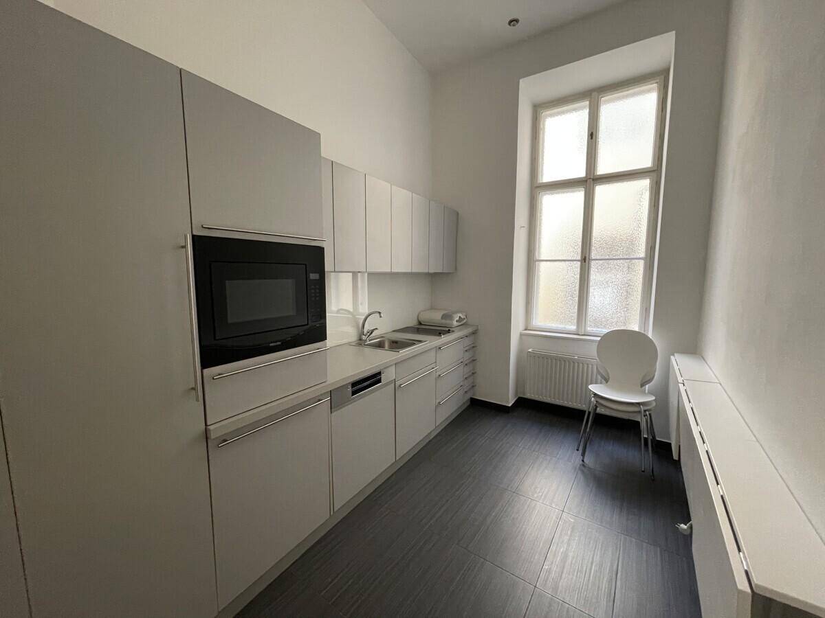 Moderne Küchenzeile mit grauen Schränken, integriertem Backofen und einem Fenster.