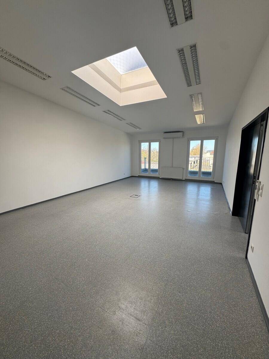 Geräumiger, heller Raum mit Oberlicht, großen Fenstern und modernem Vinylboden, ideal für Büro oder Studio.