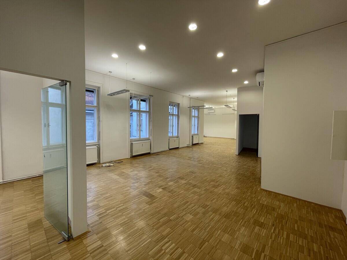 Heller und weitläufiger Bürobereich mit Parkettboden und moderner Beleuchtung.