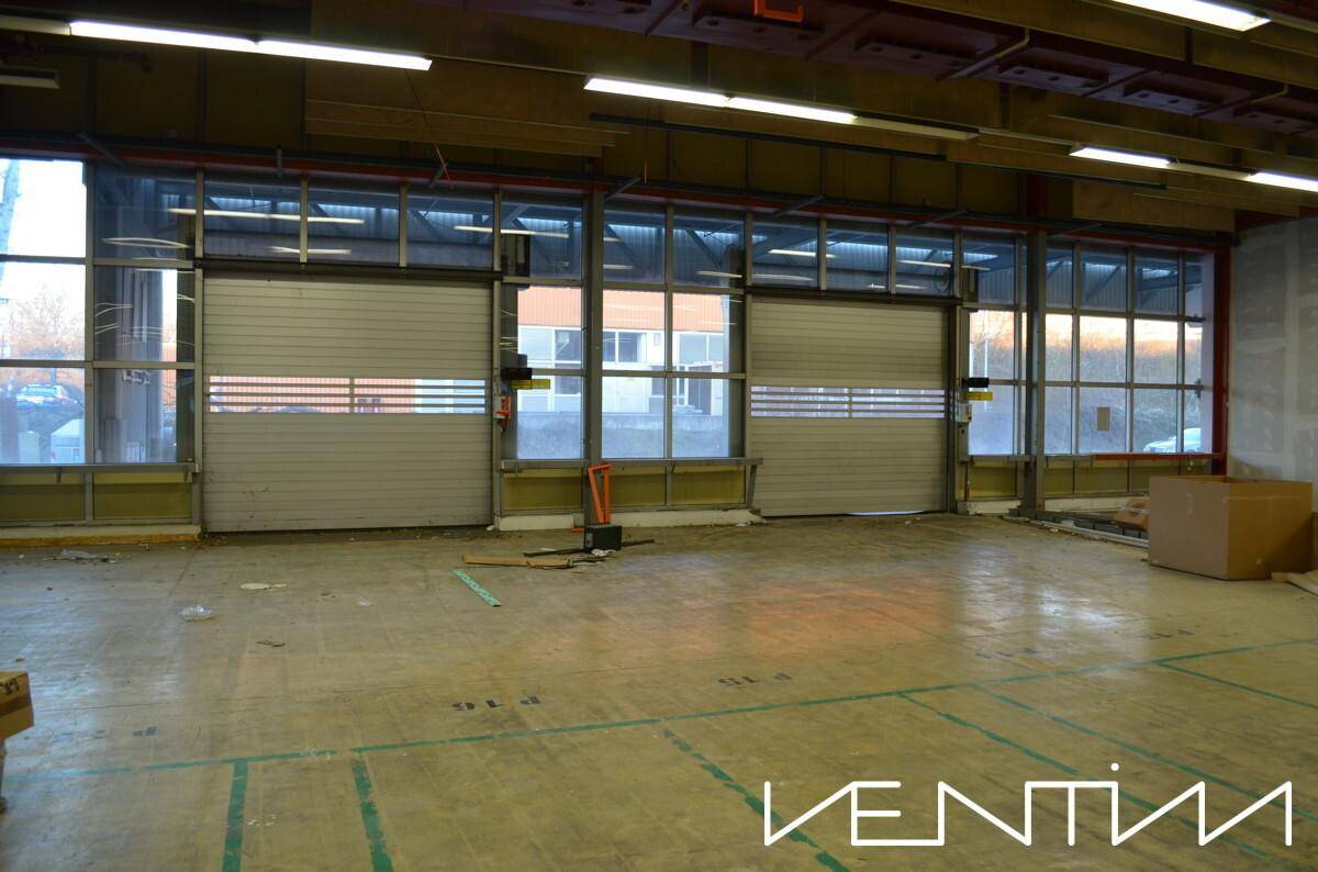 Ladebereich einer Lagerhalle mit zwei großen Rolltoren und angrenzenden Fenstern für Tageslicht.