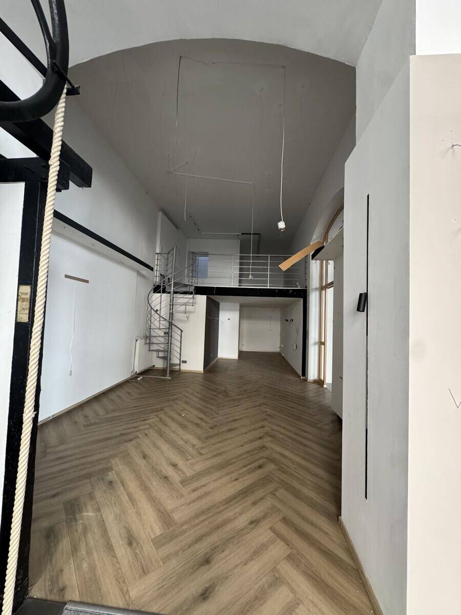 Langer, hoher Raum mit Fischgrätparkett, Wendeltreppe und einer Galerieebene, ideal für ein Loft-Konzept.