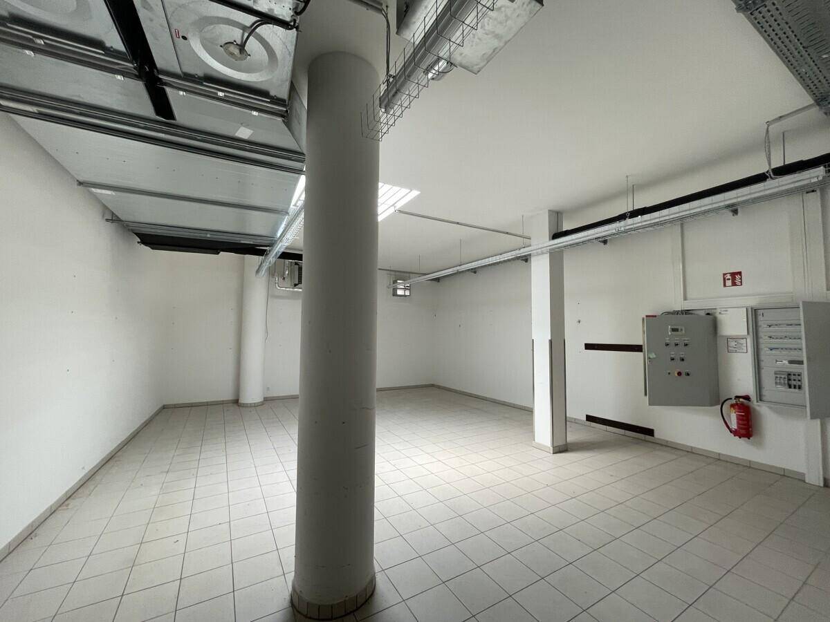 Lagerraum mit Säule, Fliesenboden, technischen Installationen und Feuerlöscher an der Wand.