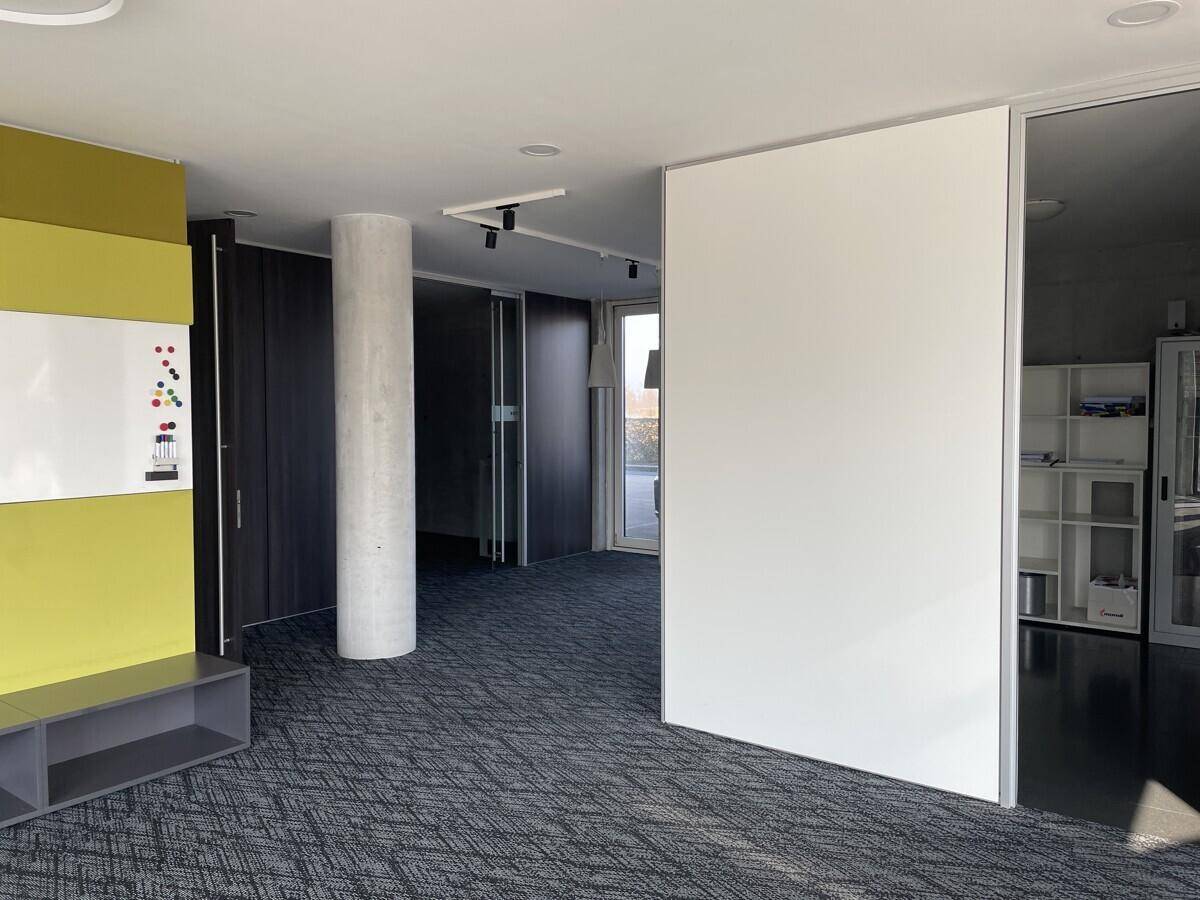 Moderner Bürobereich mit Teppichboden, farbigen Akzentwänden und integrierten Schränken, ideal für Teamarbeit.