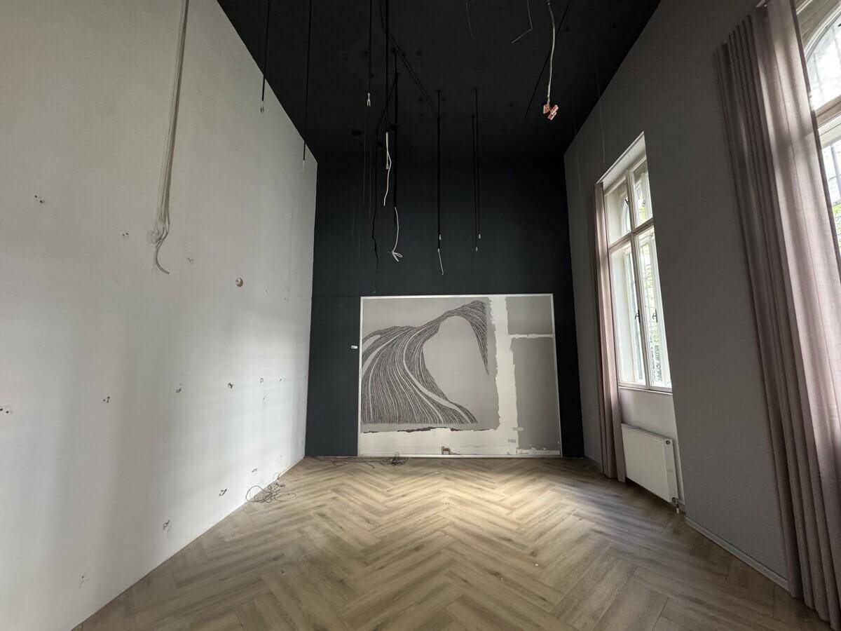 Raum in Renovierung mit Fischgrätparkett, dunkler Decke und großen Fenstern mit Vorhängen, die Tageslicht spenden.