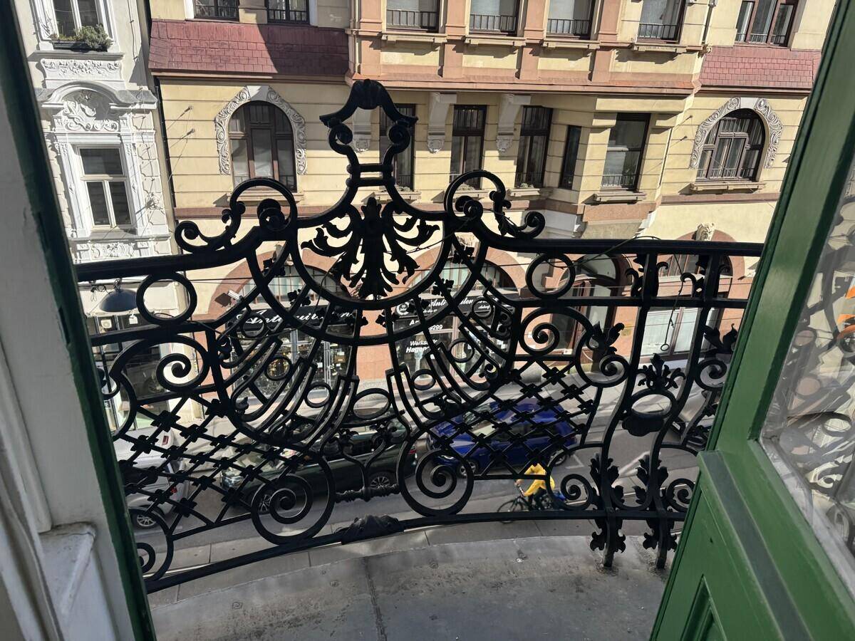 Balkon mit kunstvollem schmiedeeisernem Geländer und Blick auf die gegenüberliegenden historischen Gebäude der Stadt.
