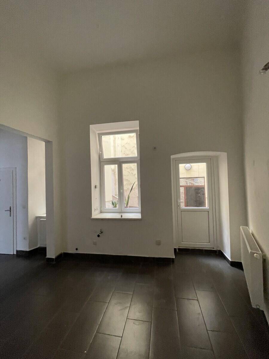 Innenraum des Gewerbeobjekts mit einem Fenster und einer Hintertür, die zu einem Hof führt.