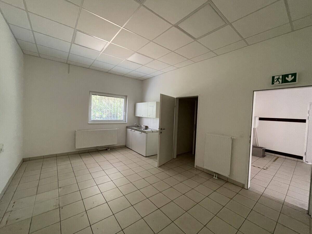 Kleiner Raum mit einfacher Küchenzeile, Fenster und Zugang zu weiteren Räumen.