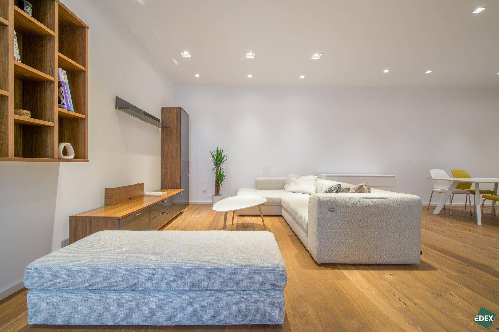 Geräumiger Wohn-Essbereich mit hellem Sofa, Holzboden und moderner Einrichtung.