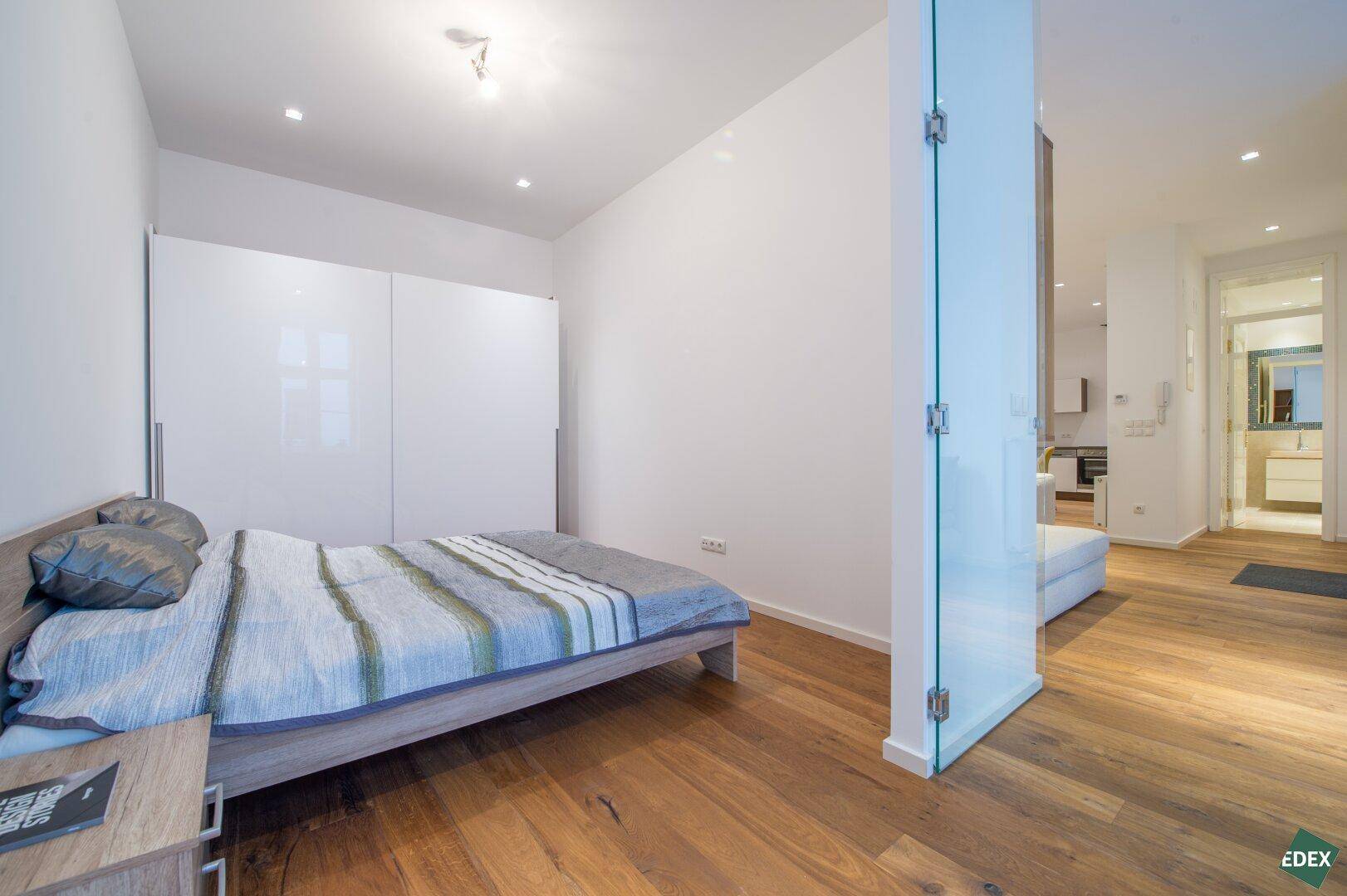 Helles Schlafzimmer mit Holzboden, Doppelbett und weißem Kleiderschrank.