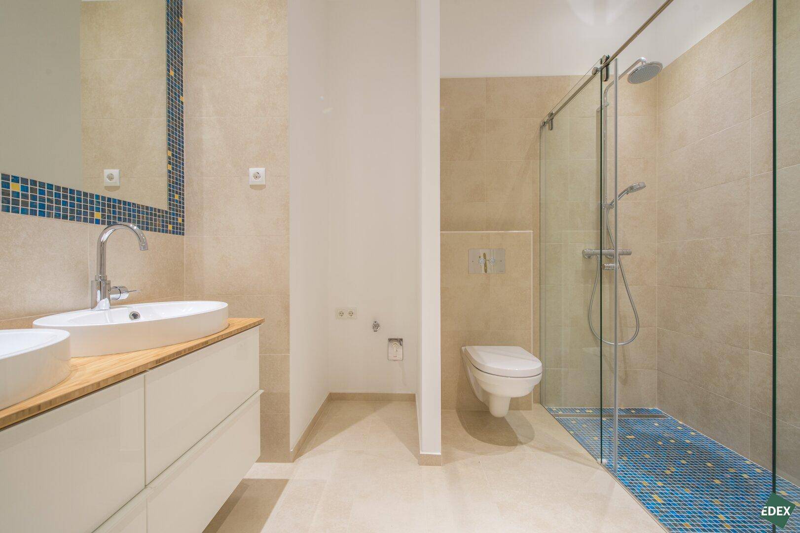 Begehbare Dusche mit Glaswand und wandhängendem WC in modernem Badezimmer.
