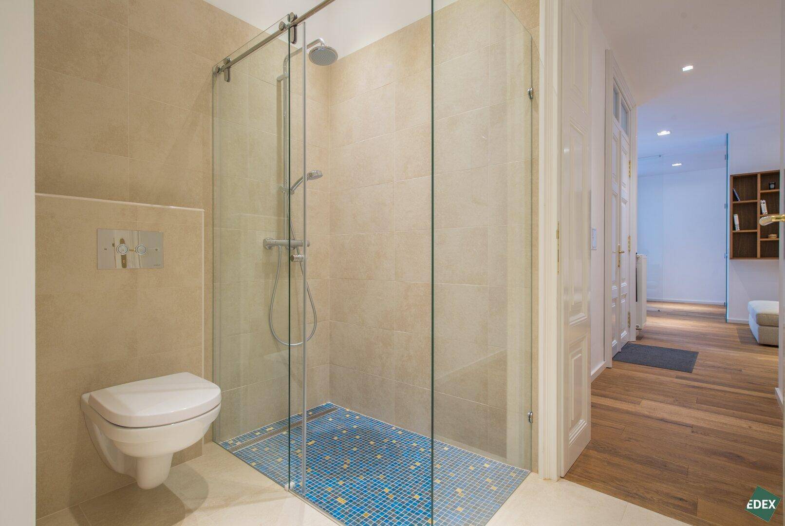 Modernes Badezimmer mit begehbarer Dusche und Blick in den Flur.