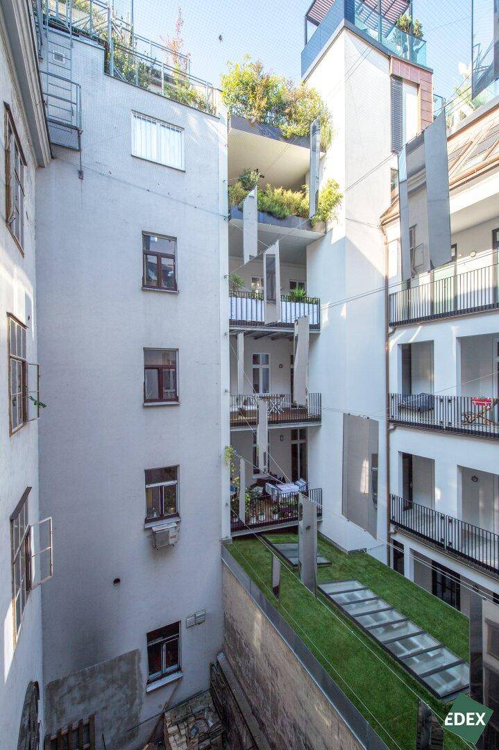 Innenhof eines Gebäudes mit mehreren Balkonen und begrünten Terrassen.