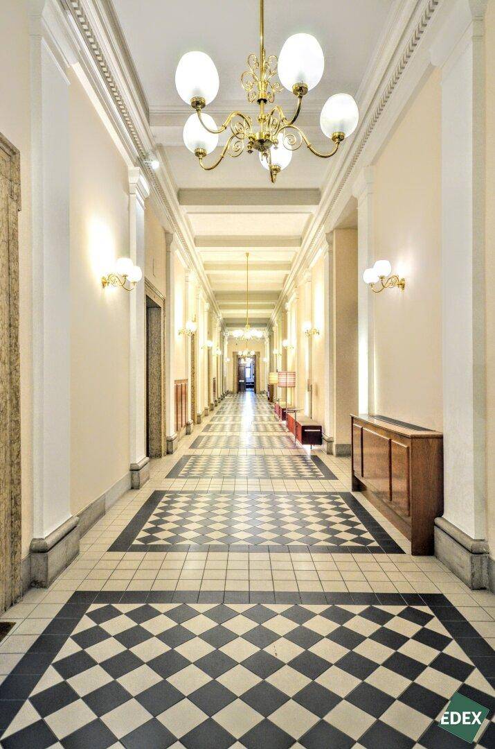Langer, eleganter Flur mit schwarz-weißem Schachbrettmuster-Fliesenboden und prunkvollen Kronleuchtern.