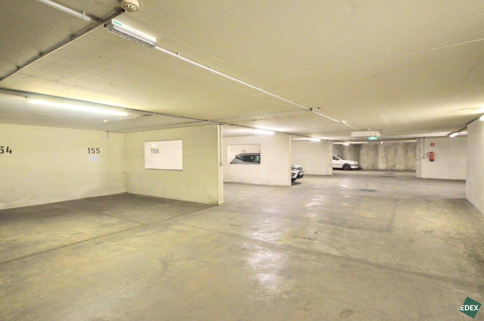 Weitläufige Tiefgarage mit leeren und belegten Parkbuchten, gekennzeichnet durch Nummern an den Wänden.