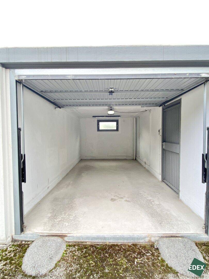 Offene Garage mit Betonboden und einem kleinen Fenster im hinteren Bereich.