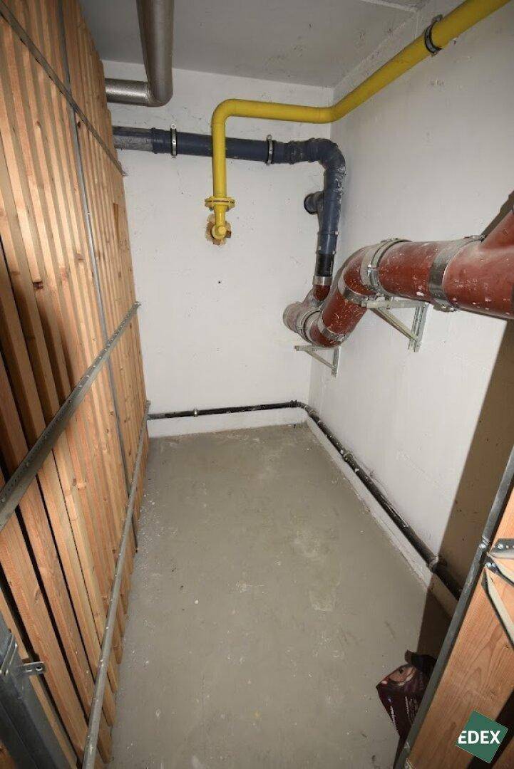 Versorgungsleitungen und Rohre in einem Kellerbereich neben den Lagerabteilen.