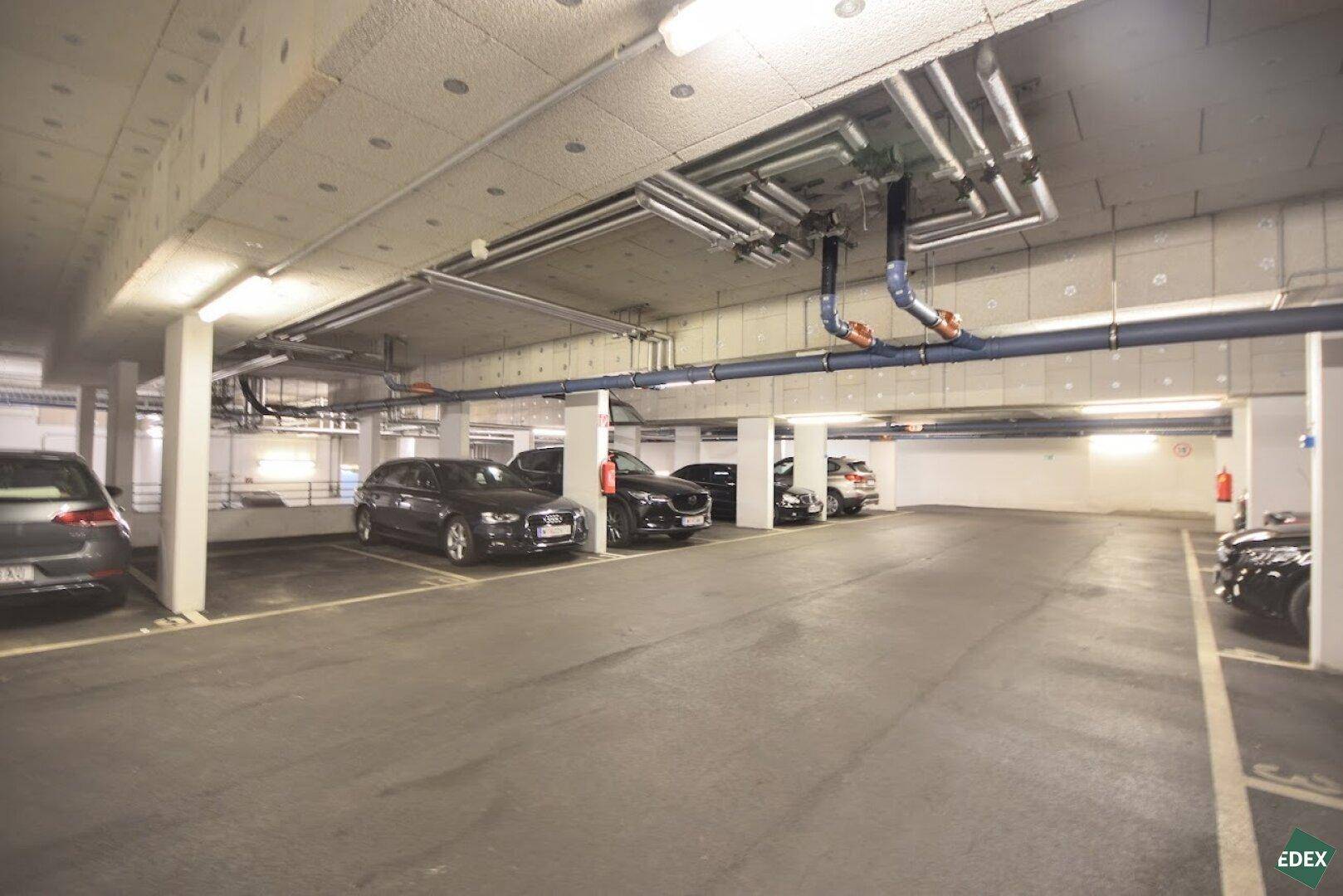 Geräumige Tiefgarage mit mehreren geparkten Fahrzeugen und guter Beleuchtung.