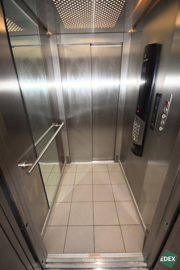 Moderner Aufzug mit Edelstahloberflächen und Fliesenboden im Gebäude.
