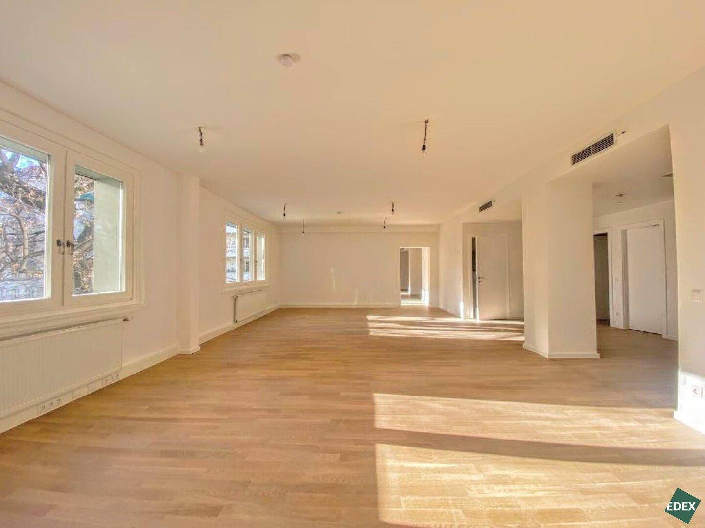 Lichtdurchfluteter, weitläufiger Raum mit Holzboden und vielen Fenstern, ideal für moderne Arbeitsumgebungen.