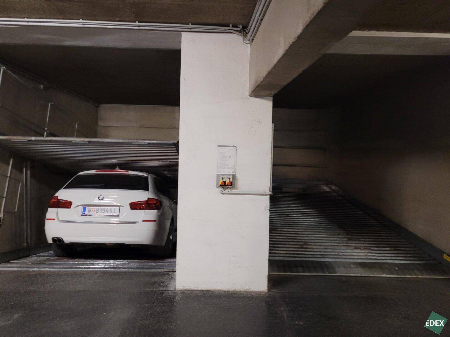 Ein Auto steht auf einer unteren Parkplattform, während die obere Plattform leer ist, daneben weitere Stellplätze.