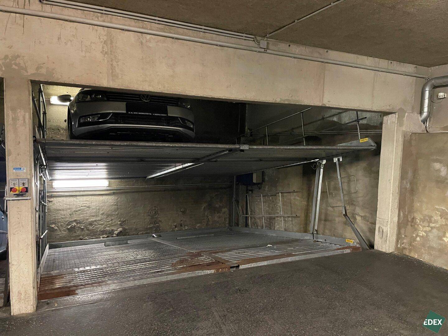 Tiefgarage mit einem Auto auf einer oberen Parkplattform und einer leeren unteren Stellfläche.