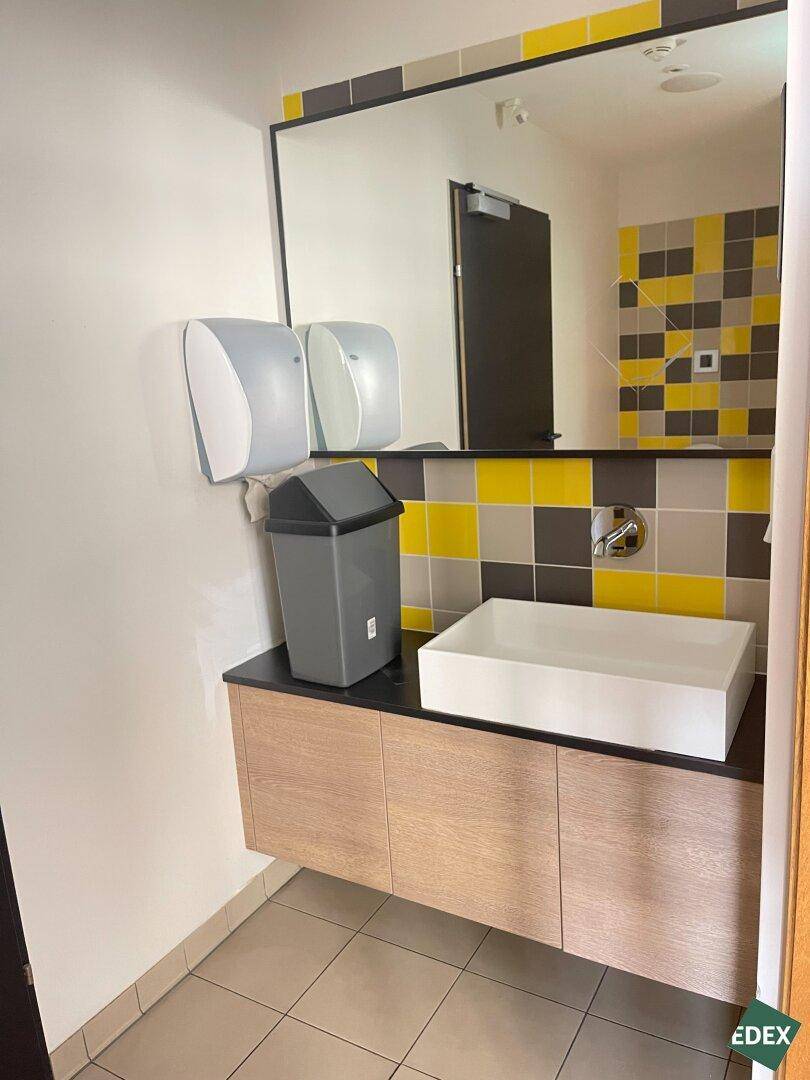 Modernes Badezimmer mit gelb-grauen Fliesen, einem Aufsatzwaschbecken und großem Spiegel.