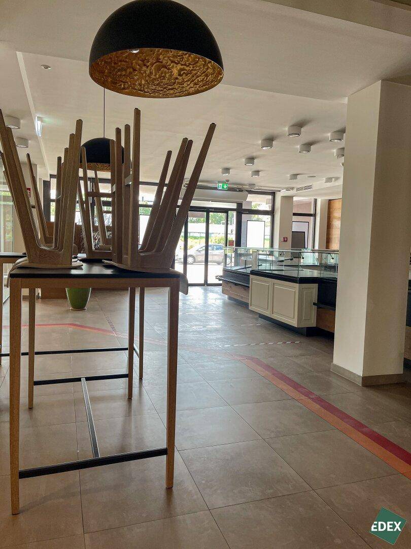 Geräumiger Ladenbereich mit hohen Decken, Fliesenboden und Verkaufstheken im Hintergrund, bereit zur Nutzung.