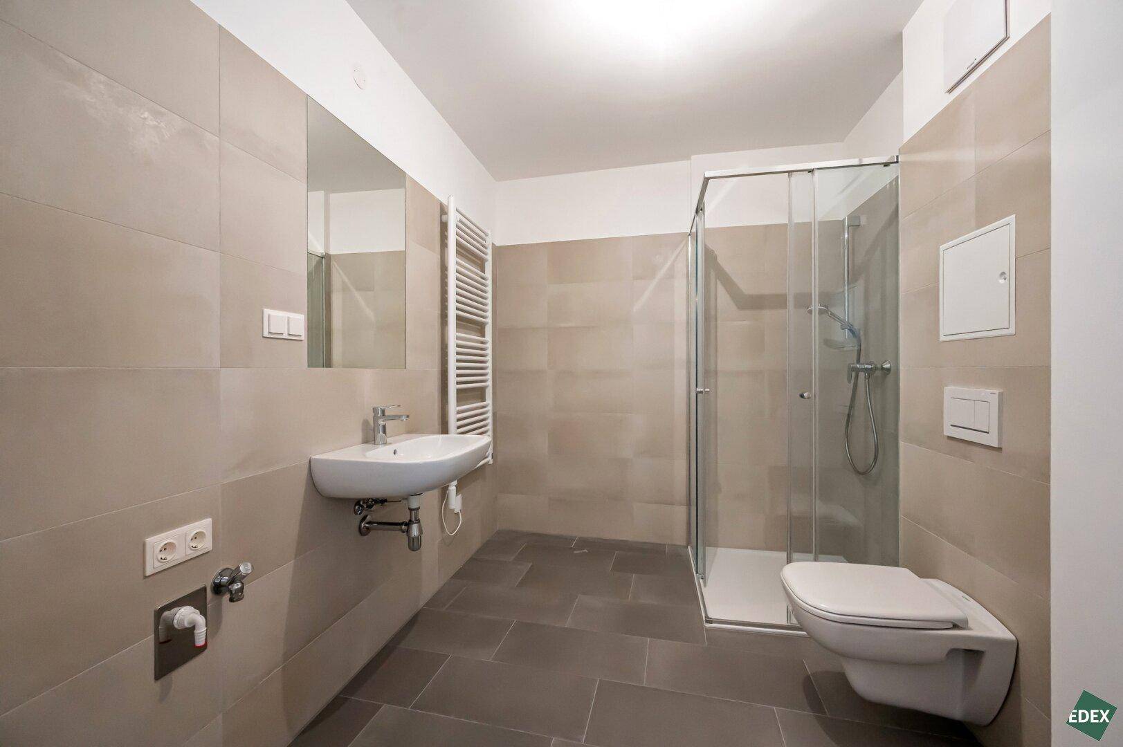Modernes Badezimmer mit begehbarer Dusche, Wand-WC und beheiztem Handtuchhalter in neutralen Farbtönen.