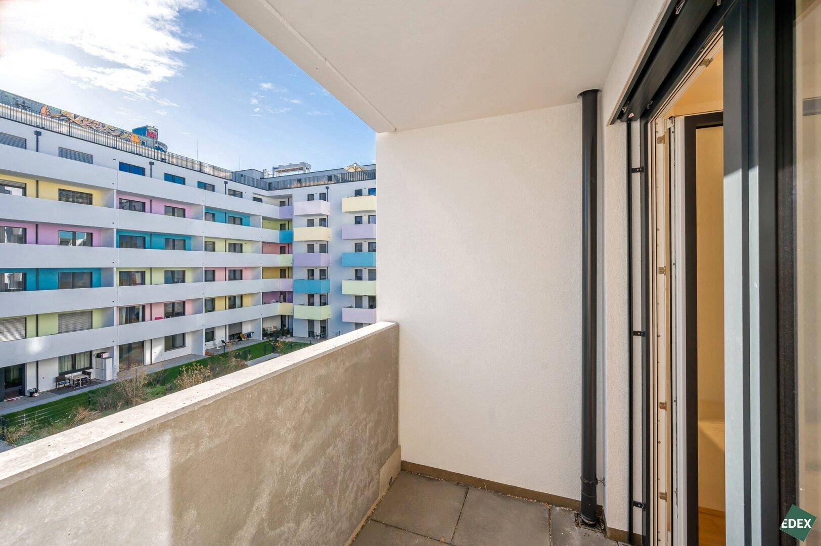 Balkon mit Blick auf den farbenfrohen Innenhof des modernen Wohnkomplexes.