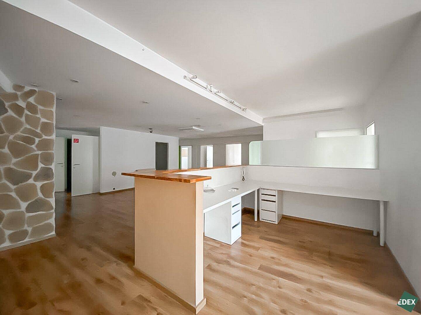 Moderner Bürobereich mit Holzfußboden, Empfangstheke und integrierten Arbeitsplätzen.