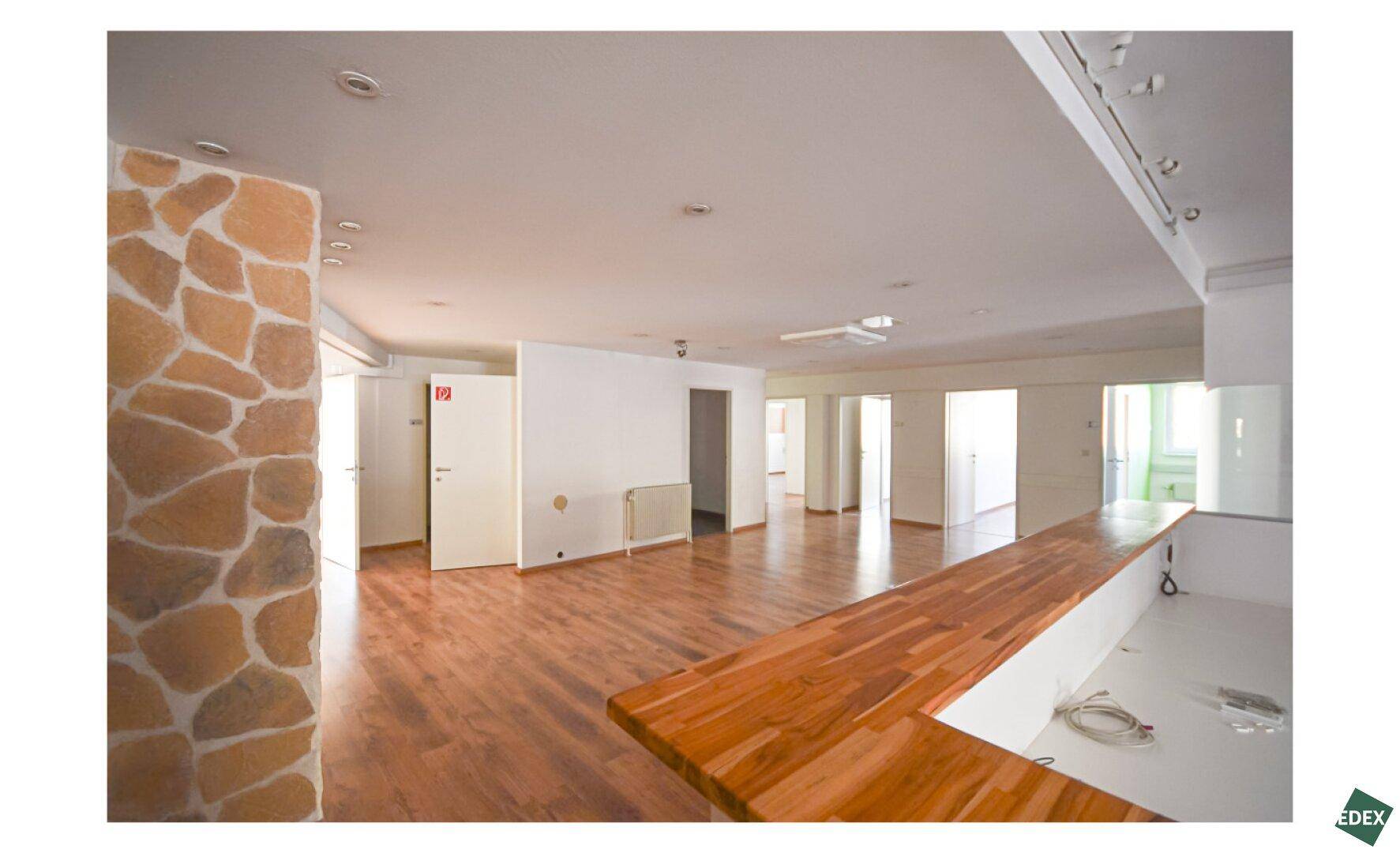 Offener Bürobereich mit rustikaler Steinwand, Holzfußboden und einer langen Holztheke.