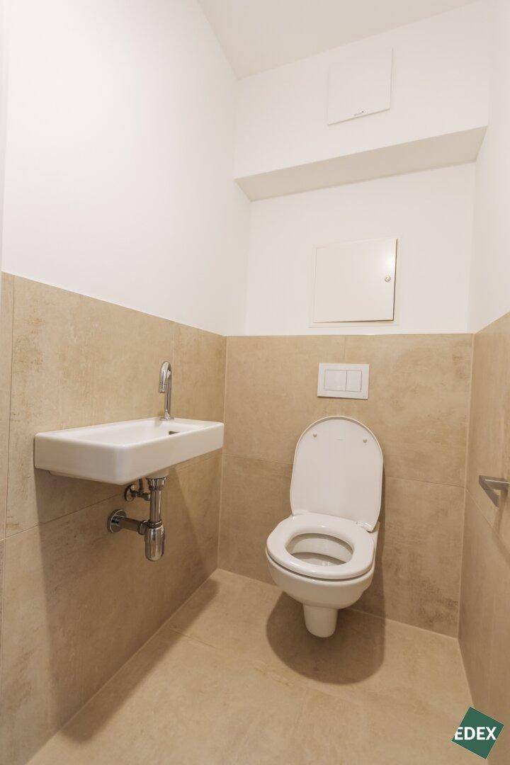 Separate Gästetoilette mit modernem Waschbecken und Wand-WC.