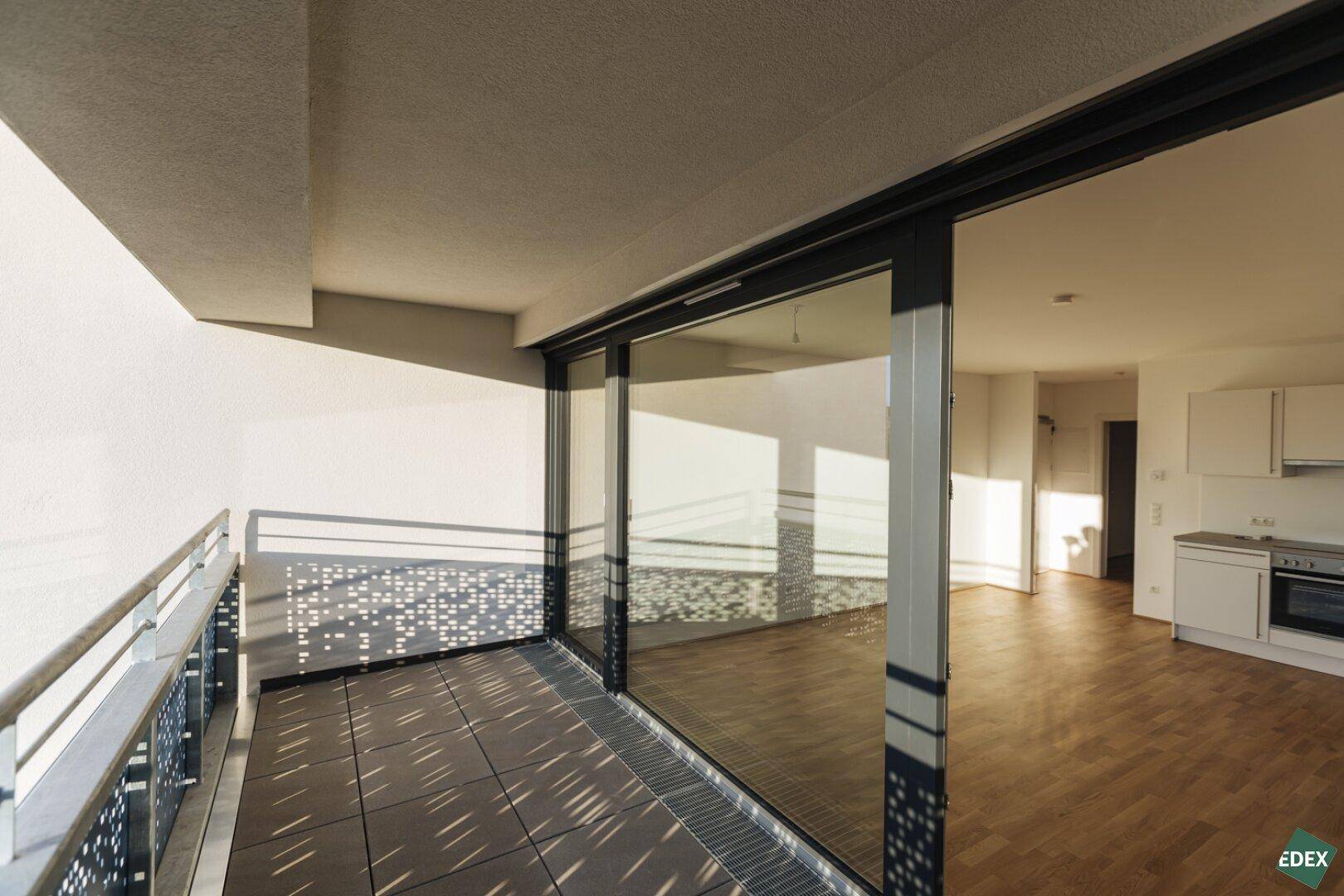 Heller Wohnbereich mit Zugang zum Balkon und integrierter Küchenzeile.