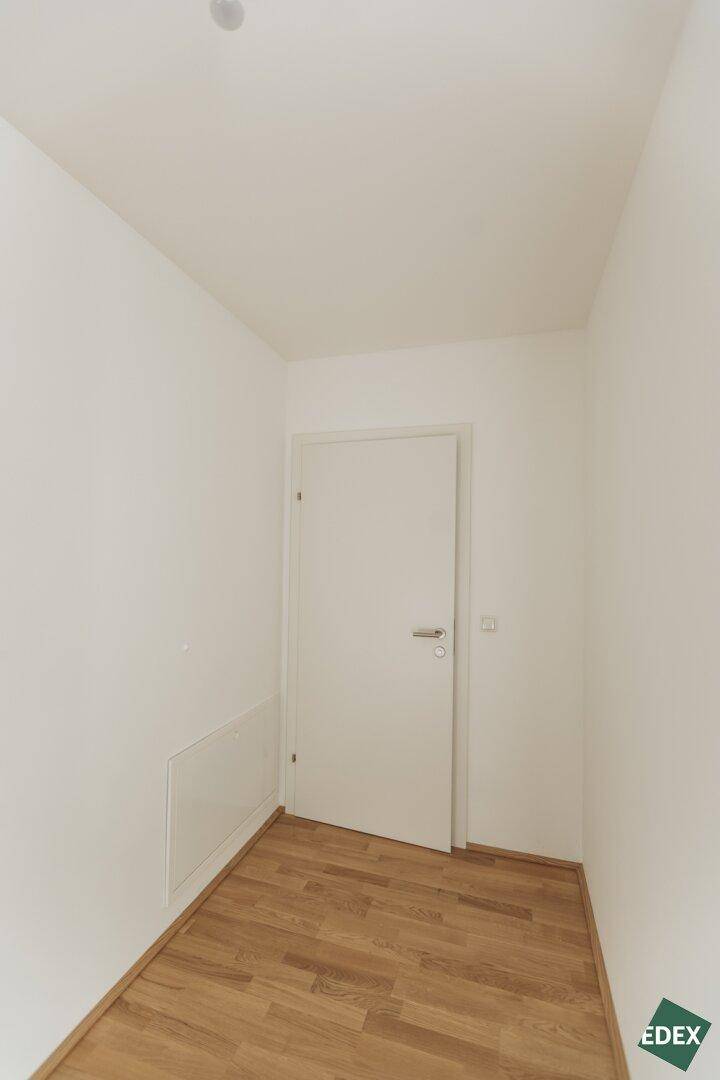 Heller Flur mit Holzboden und weißer Tür.
