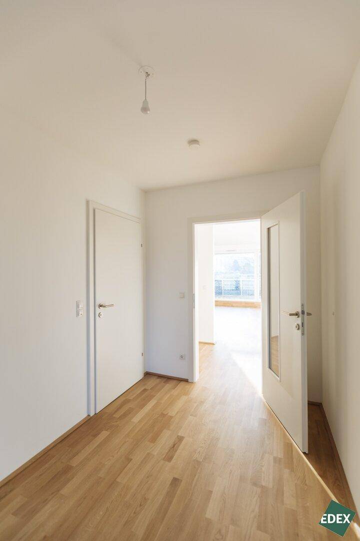 Heller Flur mit Holzboden und Zugang zu verschiedenen Räumen.