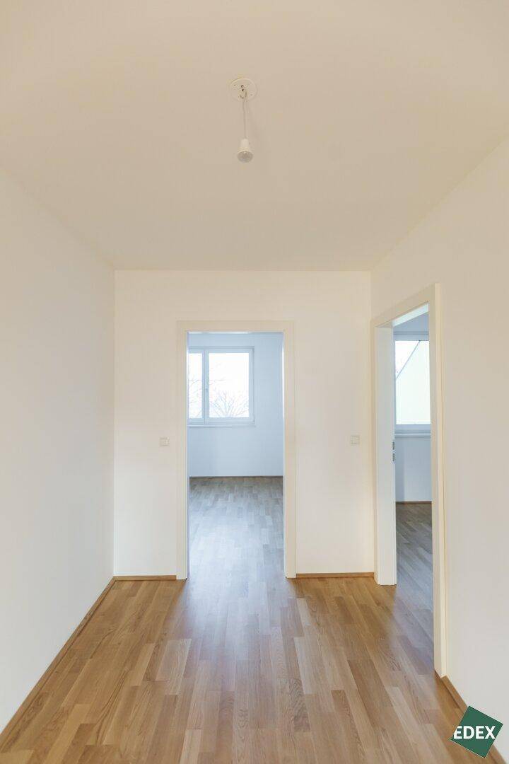 Heller Flur mit Holzboden und Blick in angrenzende Zimmer.