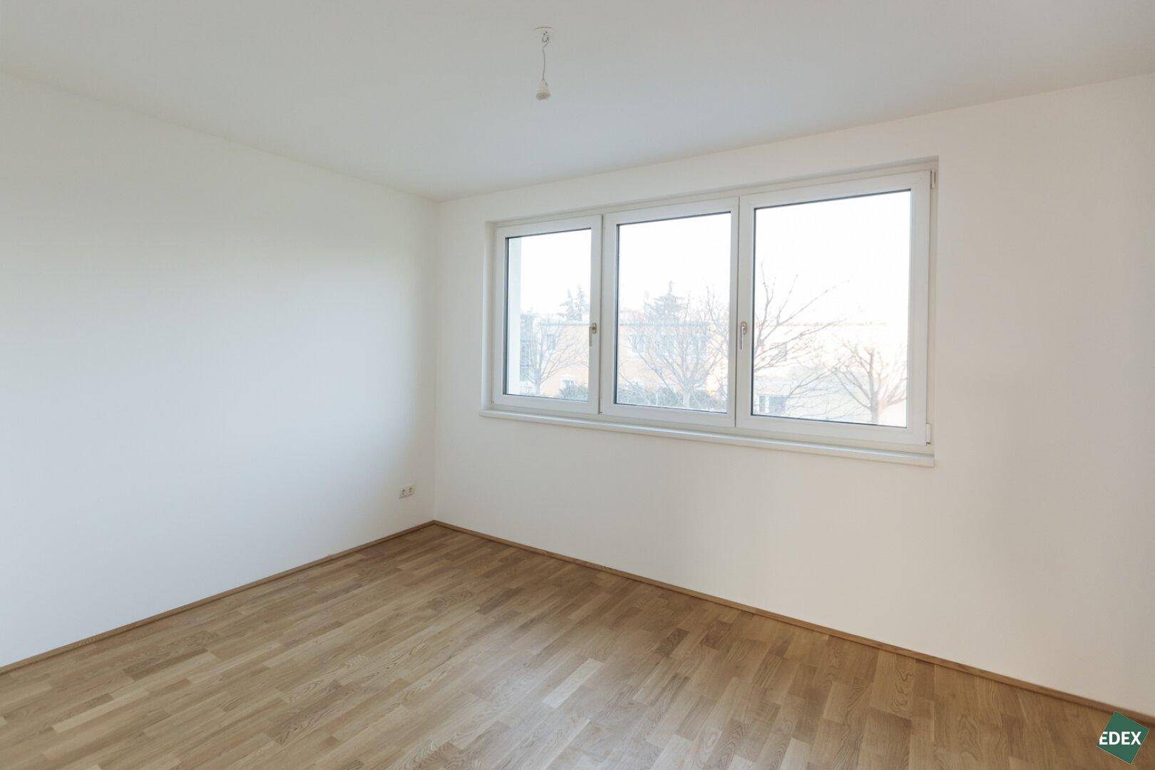 Helles Schlafzimmer mit Holzboden und großem Fenster.